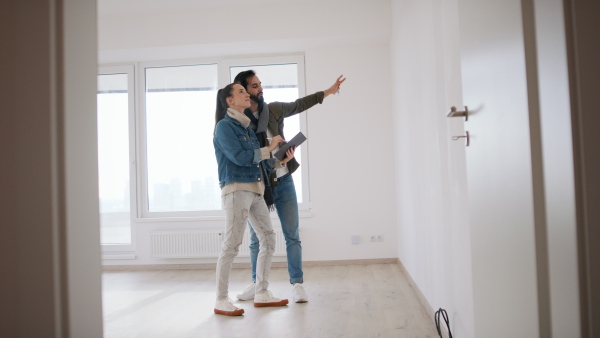 Happy young couple with tablet moving and planning in new flat, new home and relocation concept.