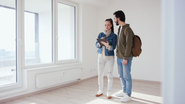 Happy young couple with tablet moving and planning in new flat, new home and relocation concept.