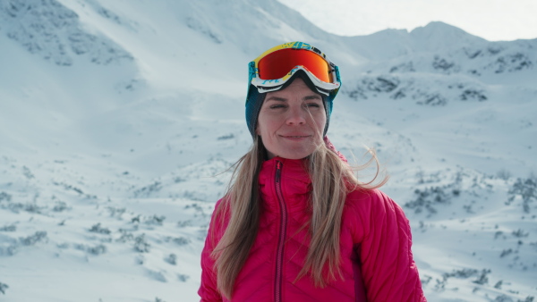 A close-up of female alpine skier looking at snowy mountains.