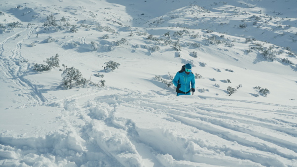 A male backcountry skier hiking to the summit of a snowy peak in the Swiss Alps