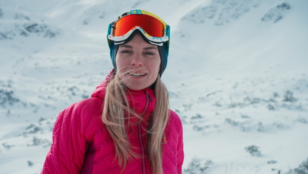 A close-up of female alpine skier looking at snowy mountains.