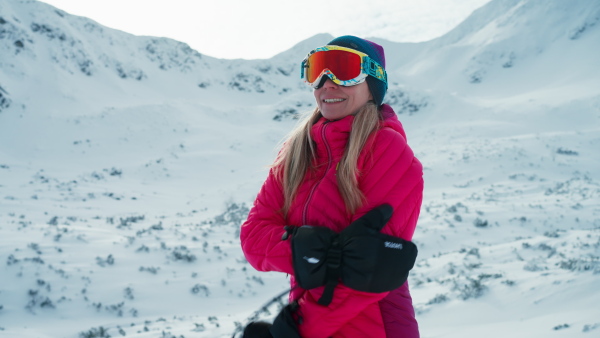 A close-up of female alpine skier looking at snowy mountains.