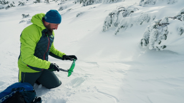 A skier using shovel to dig the snow after avalanche.