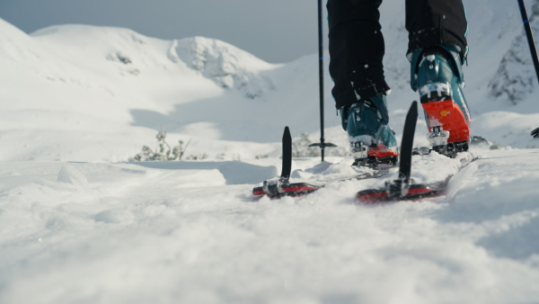 A lowsection of alpine skier walking up the mountain in winter nature.