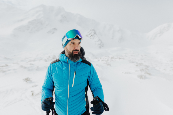 A male backcountry skier hiking to the summit of a snowy peak in the Swiss Alps