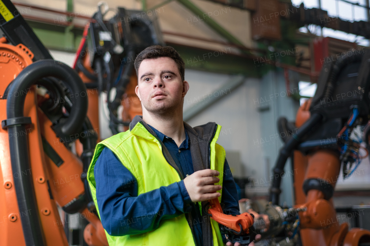 A young man with Down syndrome working in industrial factory, social integration concept.