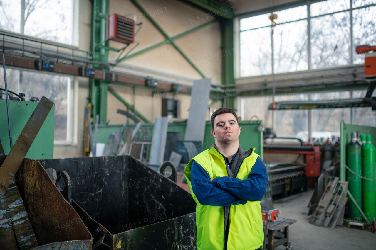 A young man with Down syndrome working in industrial factory, social integration concept.