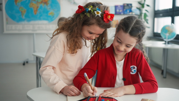 A schoolgirl helping to learn to new Ukrainian classmate, concept of enrolling Ukrainian kids to schools.