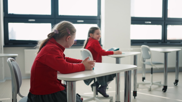 A Down syndrome schoolgirl using tablet during class at school, integration concept.