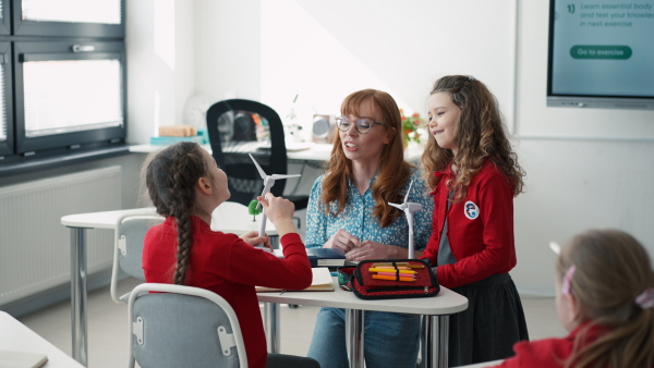 A teacher listening schoolgirl in classroom, science lesson.