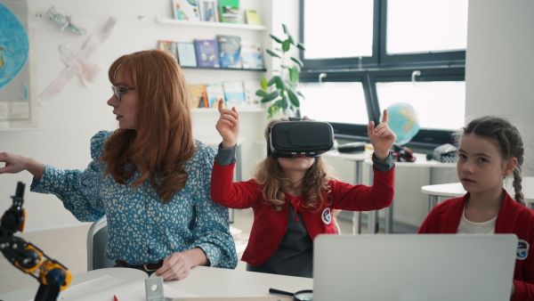 Happy schoolchildren wearing a virtual reality goggles at school in computer science class