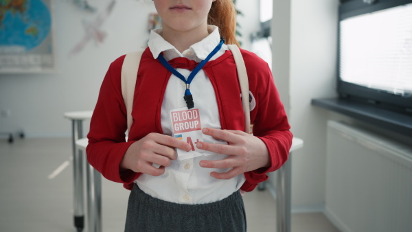 A schoolgirl with blood type sticker at school, Ukrainian war concept.