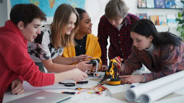 A group of students building and programming electric toys and robots at robotics classroom