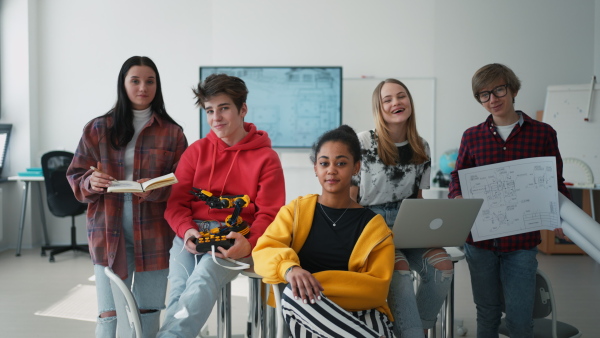 Group of students sitting and posing together in a robotics classroom