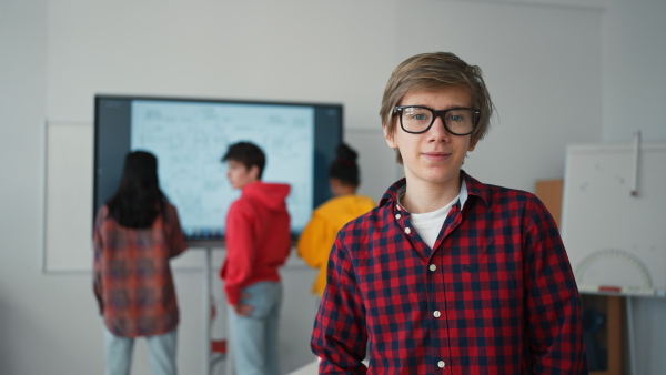 A happy teenage student looking at camera and smiling in classroom.