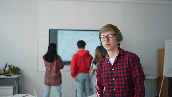 A happy teenage student looking at camera and smiling in classroom.