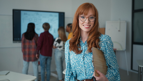 A young happy teacher looking at camera and smiling in classroom.