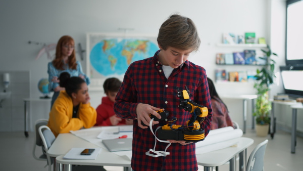 A college student presenting his builded robotic toy to young science teacher at robotics classroom at school.