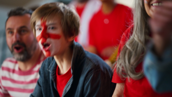 Excited football fans supproting an English national team in live soccer match at stadium.