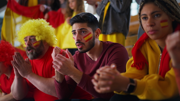 Dissapointed football fans supproting spanish national team in live soccer match at a stadium.