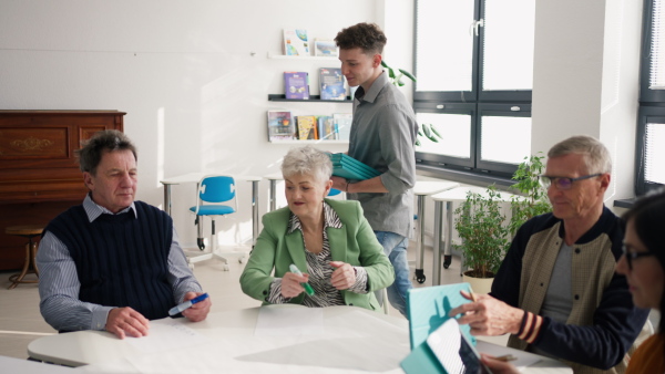 A group of seniors attending IT class in community centre with teacher