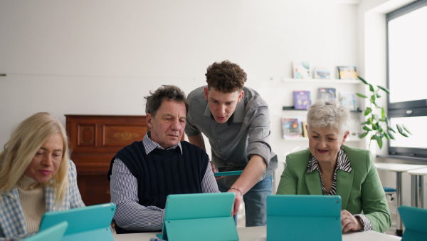 A group of seniors attending IT class in community centre with teacher