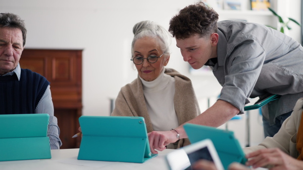 A group of seniors attending IT class in community centre with teacher