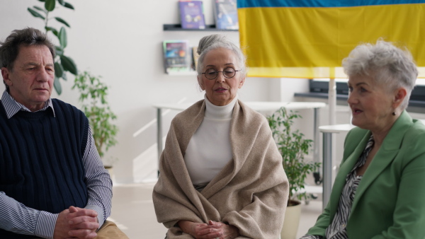 A group of seniors praying for Ukraine together in church community center.