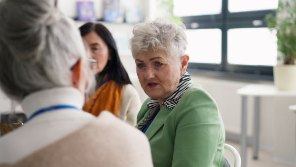 A group of senior people sitting in circle and discussing some problems together during therapy session