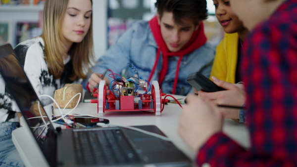 A group of high school students building and programming electric toys and robots at robotics classroom