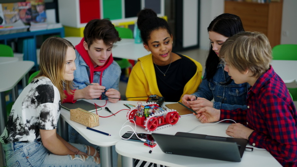 A group of high school students building and programming electric toys and robots at robotics classroom