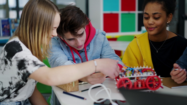 A group of high school students building and programming electric toys and robots at robotics classroom