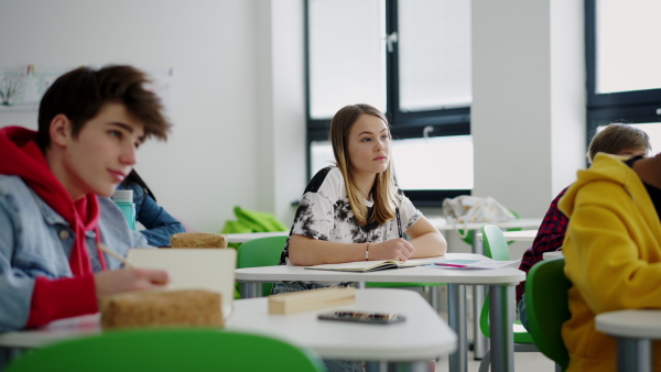 High school students paying attention in a class, sitting in their desks and writing notes.