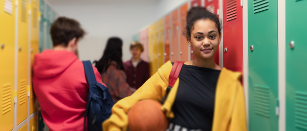 Young high school students meeting and greeting near locker in a campus hallway, back to school concept.