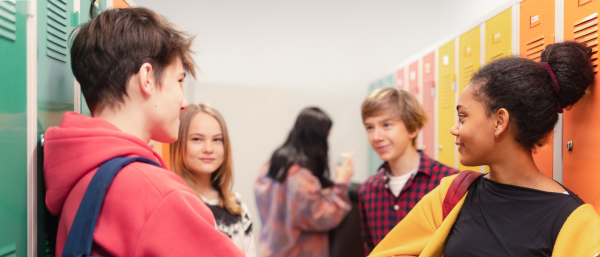 Young high school students meeting and greeting near locker in a campus hallway, back to school concept.