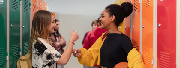 Young high school students meeting and greeting near locker in a campus hallway, back to school concept.