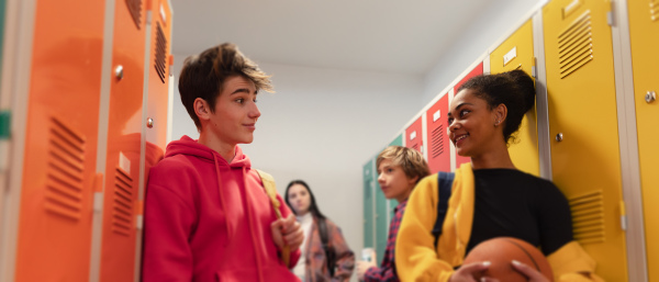 Young high school students meeting and greeting near locker in a campus hallway, back to school concept.