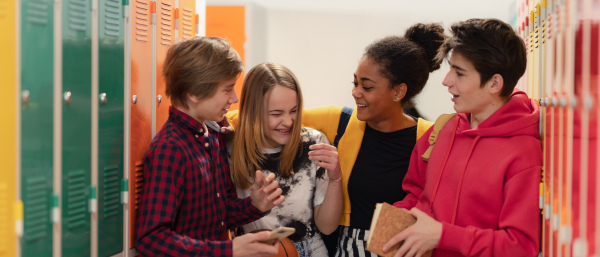 Young high school students meeting and greeting near locker in a campus hallway, back to school concept.