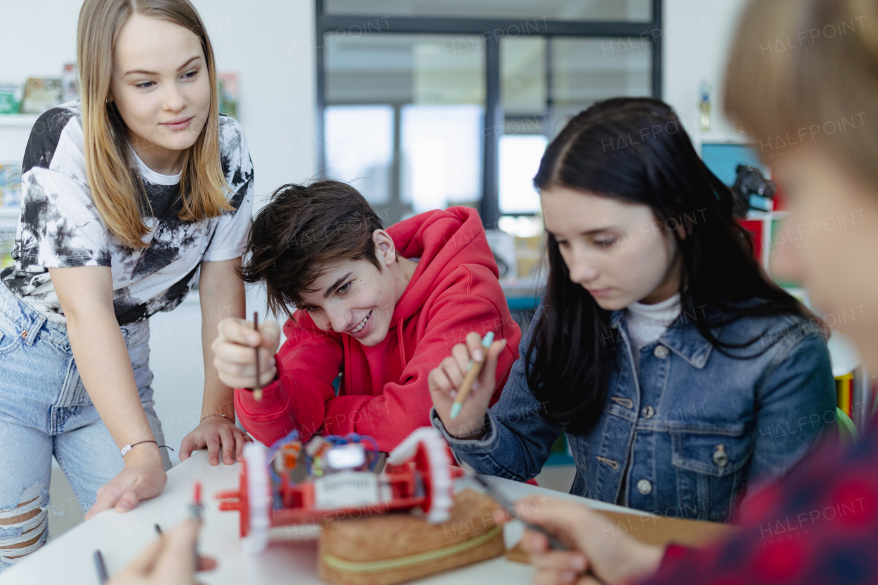 A group of high school students building and programming electric toys and robots at robotics classroom