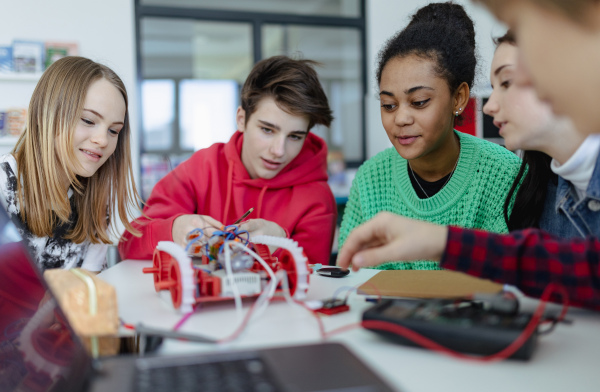 A group of high school students building and programming electric toys and robots at robotics classroom