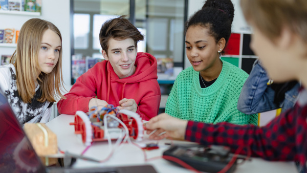 A group of high school students building and programming electric toys and robots at robotics classroom