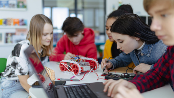 A group of high school students building and programming electric toys and robots at robotics classroom