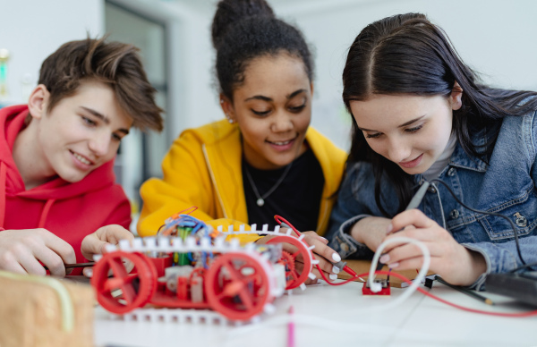 A group of high school students building and programming electric toys and robots at robotics classroom