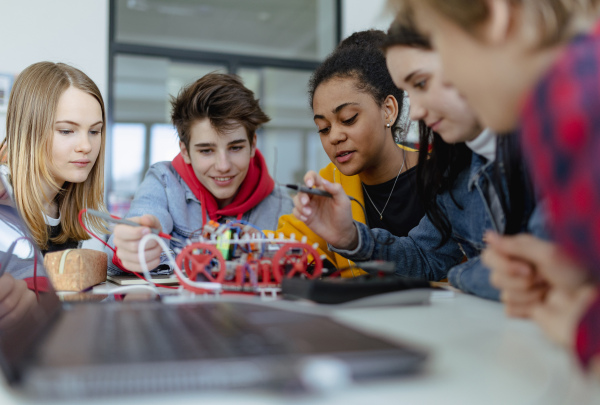 A group of high school students building and programming electric toys and robots at robotics classroom