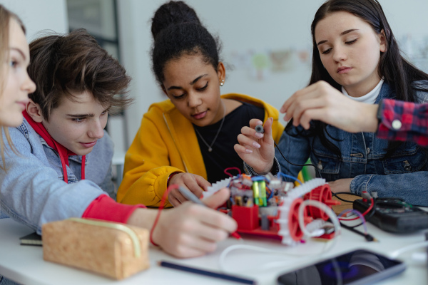 A group of high school students building and programming electric toys and robots at robotics classroom