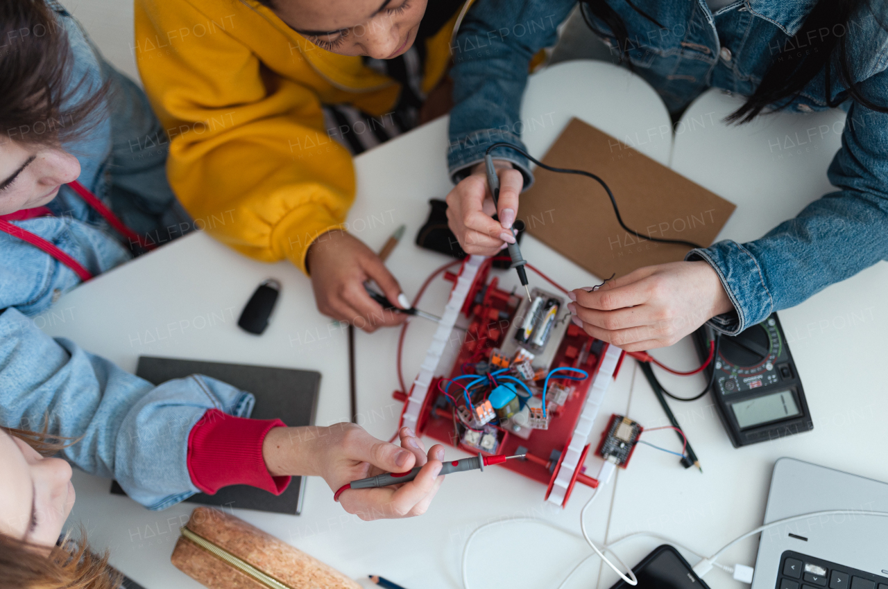 A group of high school students building and programming electric toys and robots at robotics classroom