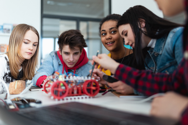 A group of high school students building and programming electric toys and robots at robotics classroom