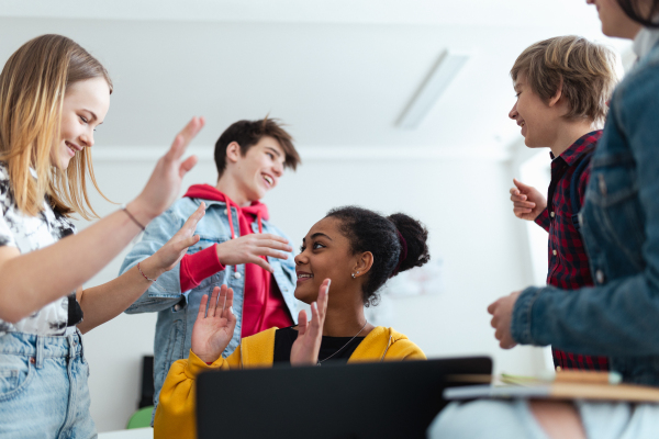 A high school students meeting and greeting in classroom after school holidays, back to school concept.