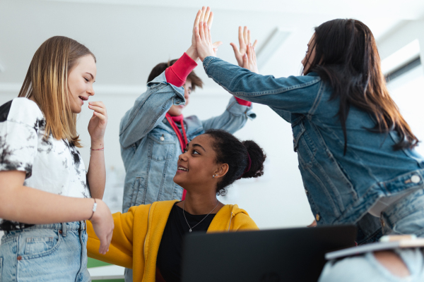 A high school students meeting and greeting in classroom after school holidays, back to school concept.