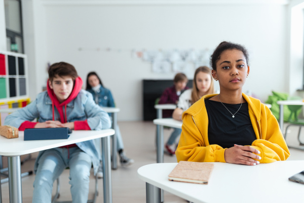 High school students paying attention in a class, sitting in their desks and writing notes, back to school concept.